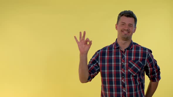 Happy Young Man Making 'Okay' Hand Sign on Yellow Background