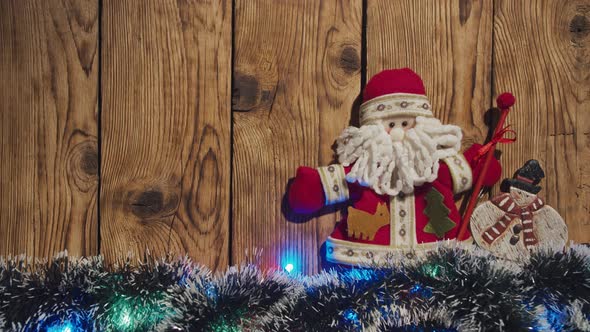 Top View of Christmas Wooden Vintage Background Is Decorated with Blinking Garlands, Toy Santa Claus