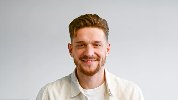 Portrait of serious bearded guy in yellow shirt looking straight