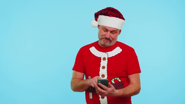 Man in Christmas Tshirt Hat Using Mobile Phone Typing New Post on Web Shopping Online Browsing
