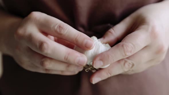 Woman in Brown Cleaning Garlic Skin in the Kitchen