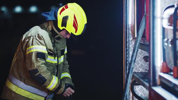 Fireman Putting on Protective Gloves in Front of the Fire Engine. Preparing for the Fire Drill