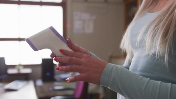 Female teacher wearing face mask holding a temperature gun