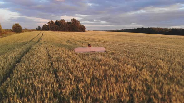 Aerial View. Girl Runs Across the Summer Field with Open Wings