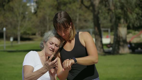 Two Sporty Women with Modern Devices in Summer Park