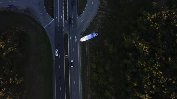 A Topdown Aerial View of an Enginepowered Paraglider Flying Over a Highway