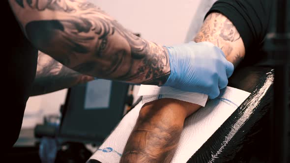 Male Tattoo Artist Tattooing a Client