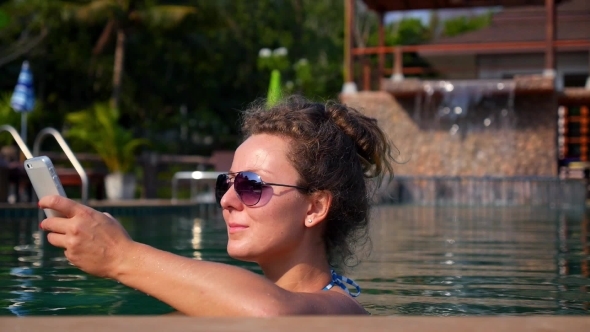 Beautiful Girl Using Smartphone In Swimming Pool