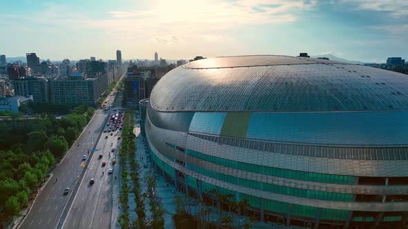 Aerial view of traffic on road in Taipei City beside modern architecture of Dome DaJudan (臺北大巨蛋) dur