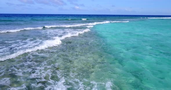 Wide above travel shot of a white sandy paradise beach and blue water background in vibrant 4K