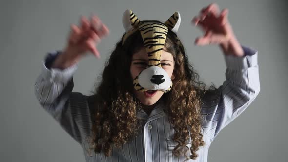 Young girl wearing tiger mask, roaring