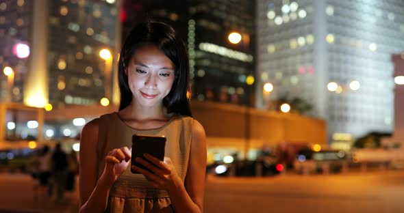 Woman using smart phone in Hong Kong at night 