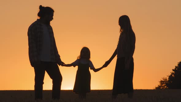 Three Silhouettes on Background of Sunset Sun Light Outdoors in Nature Standing Family with Small