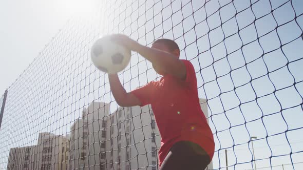 African American soccer kid in red throwing the ball in a sunny day