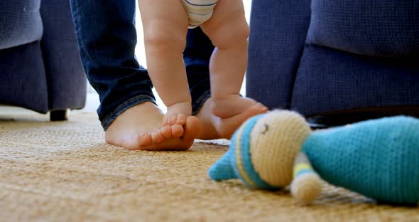 Father helping his baby boy to walk in living room 4k