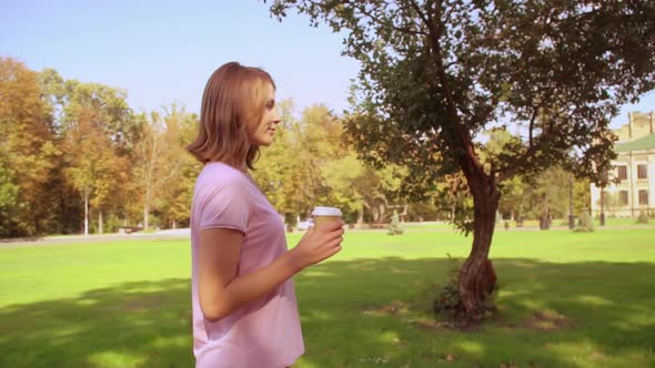 Blonde Woman Drinks Coffee in Park