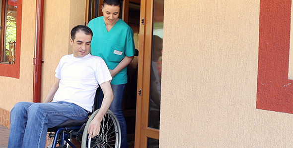 Nurse with Young Man in Wheelchair Walking