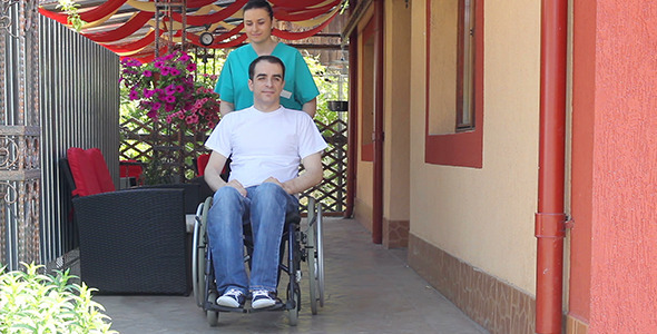 Nurse Walking with Male Patient in a Wheelchair