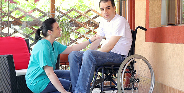 Nurse Consoling Sad Man in Wheelchair