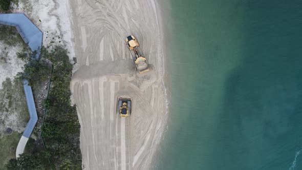 High drone view of large machinery working on a coastal rejuvenation project replenishing sand close