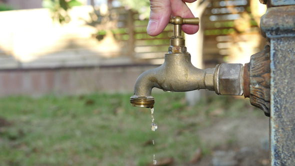 Man Opening and Closing an Old Fashioned Fountain Tap