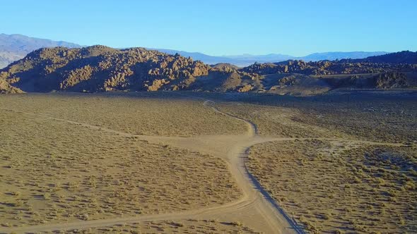 Scenic aerial drone view of dirt road and rocky desert landscape.