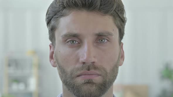 Portrait of Serious Young Man Looking at Camera