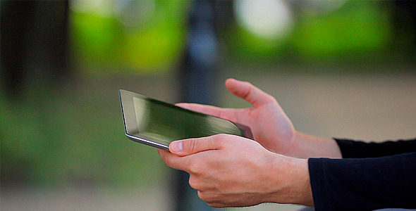 Man With the Tablet Computer on a Bench in a Park