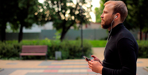 Man Listening to Music with Headphones in a Park