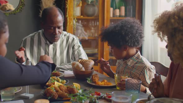 African American Man Talking with Kid at Family Dinner