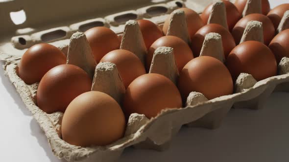 Close up of multiple eggs in a cardboard box on white surface