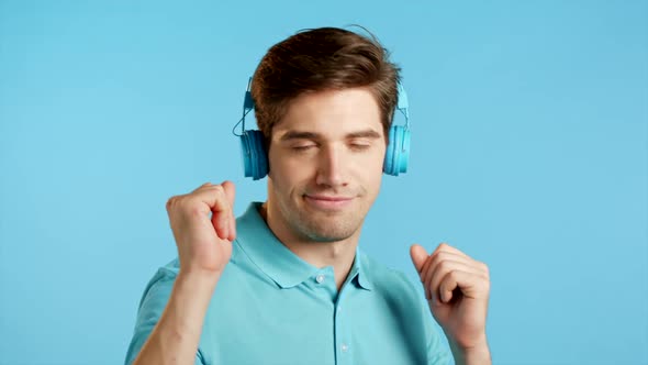 Handsome Young Man with Trendy Hairdo Having Fun, Smiling, Dancing Head with Blue Headphones in