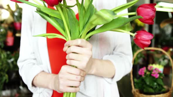 Female florist holding bunch of red flower in flower shop