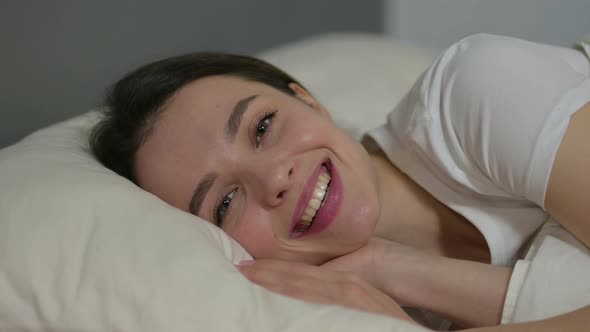 Young Woman Smiling at Camera in Bed