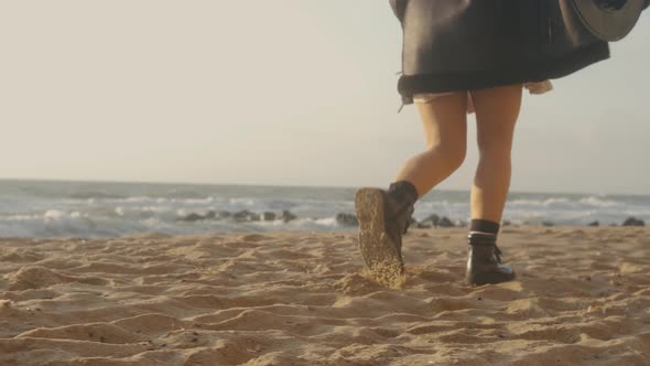 Closeup Cinematic Shot of Woman Feet in Boots Walking on the Beach at Sunset or Sunrise