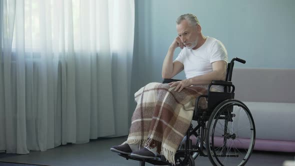 Male Pensioner Sitting in Wheelchair and Waiting for His Family at Nursing Home