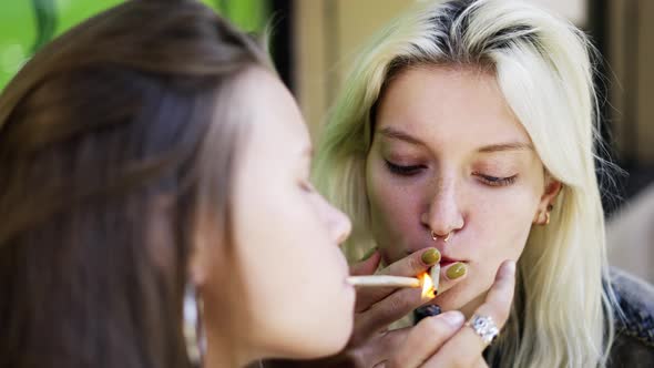 Two Girls Lighting Their Handrolled Cigarette Enjoying a Smoking Outside