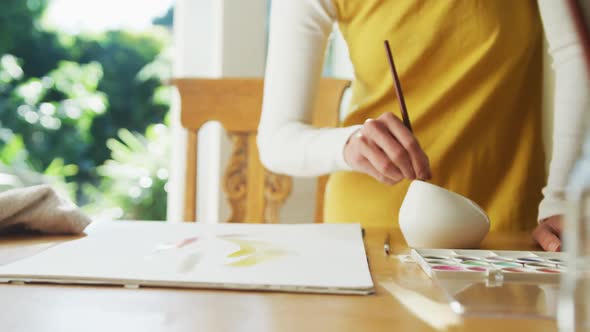 Midsection of caucasian woman painting at home