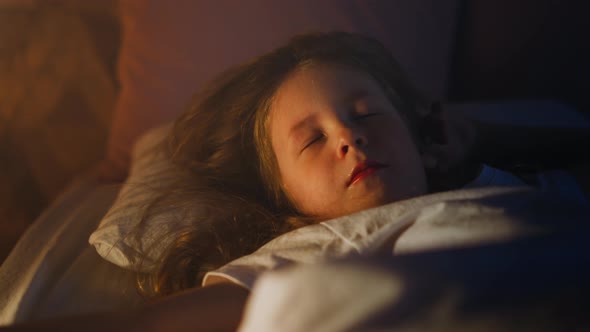 Sweet Girl Sleeps with Eyes Blinking Under Eyelids on Bed