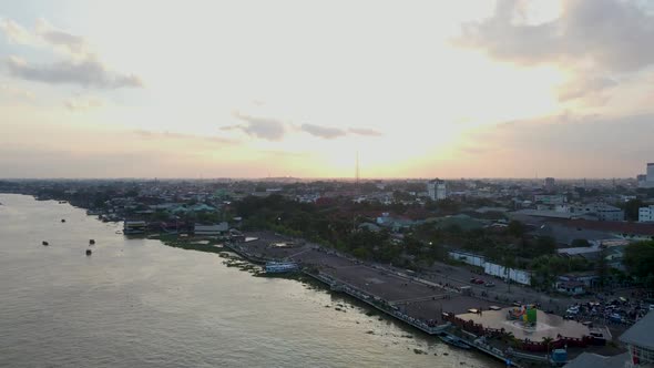 Majestic sunset over Palembang city with vast Musi river, aerial fly back view