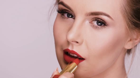 Close-up of Beautiful Woman Applying Red Lipstick and Smiling