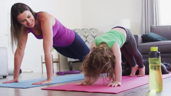 Caucasian mother and daughter practising yoga in living room