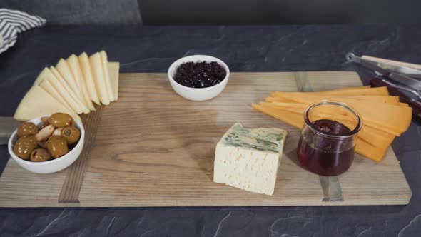 Arranging gourmet cheese, crakers, and fruits on a board for a large cheese board.
