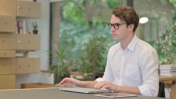 Young Man Closing Laptop and Leaving Modern Office