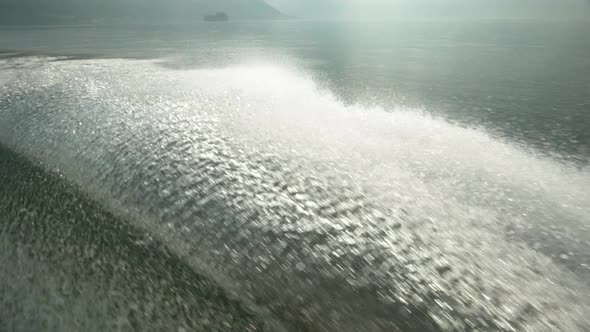 Water spray comes from a classic luxury wooden runabout boat on an Italian lake.