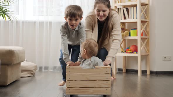 Baby boy sitting in wooden toy box while his family riding him