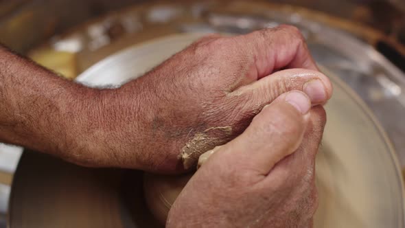 Artisan Holds Wet Piece of Clay on Pottery Wheel with Both Hands and Gives It Round Shape Closeup