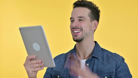 Portrait of Young Man Doing Video Chat on Tablet, Yellow Background