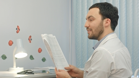 Doctor Reading Patient Card At Hospital