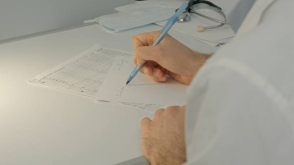 Doctor Sitting On The Desk With Paper  And Working